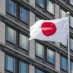 Flaga Japonii powiewa przed nowoczesnym budynkiem. Japonia liczba ludności to ponad 125 milionów osób.