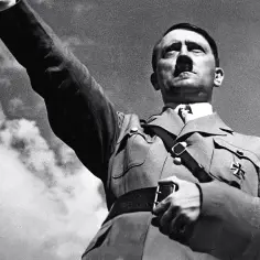 Adolf Hitler, przywódca NSDAP, wznosi rękę w geście pozdrowienia.