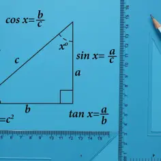Trójkąt prostokątny z wzorami: pole, sinus, cosinus i tangens kąta. Przybory geometryczne i ołówek.